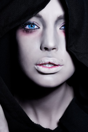 Spooky woman with intense pale face in black cape.の写真素材