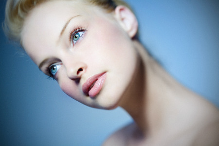 Beautiful woman on blue background. Shallow DOF and some grain. Tilt-and-shift lens used.の写真素材