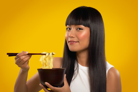 Cheerful Asian girl with noodles and chopsticks.
