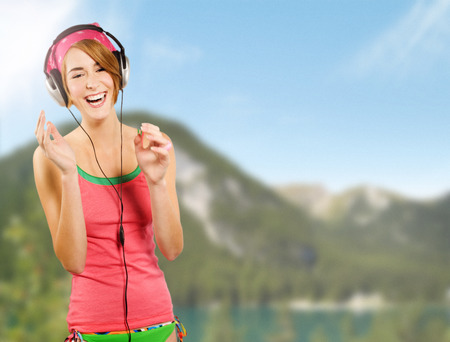 Happy girl with headphones on summer nature background.の写真素材