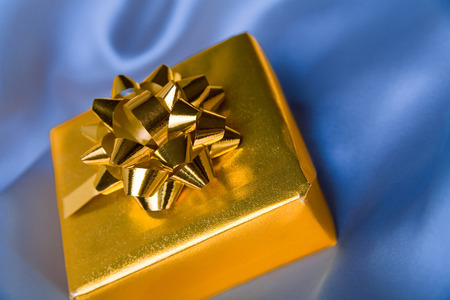 Pretty golden paper gift box on silk sheets.の写真素材
