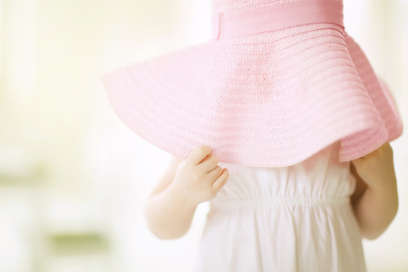 Little girl putting on large hat and hiding.の写真素材
