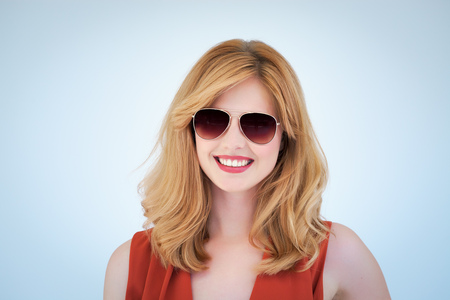 Young modern hip woman with blond hair wearing aviator sunglasses on blue background.の写真素材