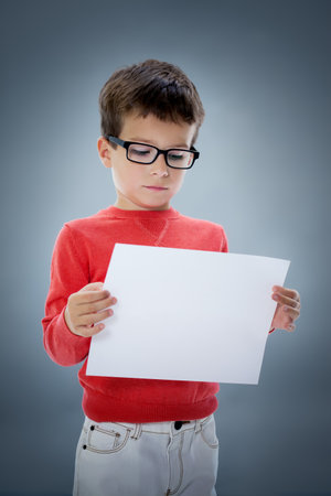 Six year old Caucasian boy in studio with blank A4 sheet of paper in hands.の写真素材