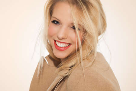 Beautiful young Caucasian woman with long blond hair and warm red lipstick in studio.の写真素材