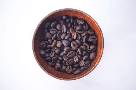 coffee beans in a wooden bowl on a white tableの写真素材