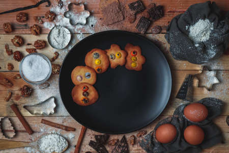 Still life making homemade cookies for Christmas with cookies, black plate, flour, egg, nuts, chocolate, grater, stick spoon, vanilla, cinnamon and molds. Top view without peopleの写真素材