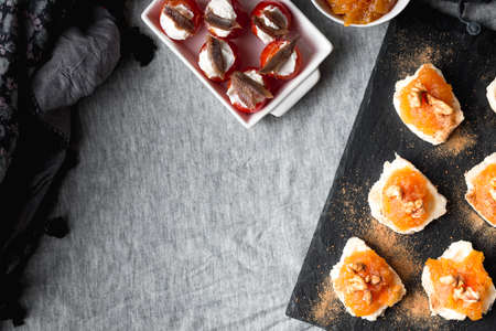 Still life of Goat roll cheese with jam and walnuts with cherry tomatoes stuffed with cheese and anchovies. Top viewの写真素材