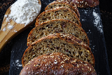 Closeup of bread with flour on slate bottom. Front view. Dark Food.