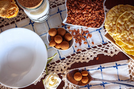 Tray with continental breakfast on hotel bed made of cereals, chocolate, cakes and a bowl with...