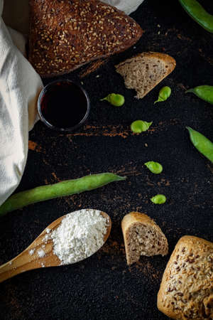 Composition of Mediaterranea table composed of bread, beans, wine and flour on a black and texturized background. Mediterranean diet. Aperitif and healthy cookingの写真素材