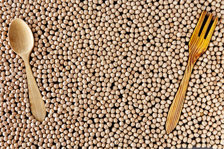 Composition of natural chickpeas with kitchen utensils, spoon and wooden fork on rustic textured bottom. View from above with space to write.の写真素材