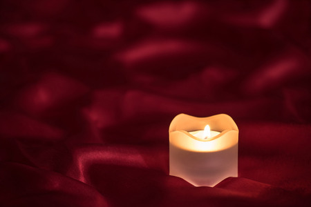 Candle on the red cloth with folds backgroundの写真素材