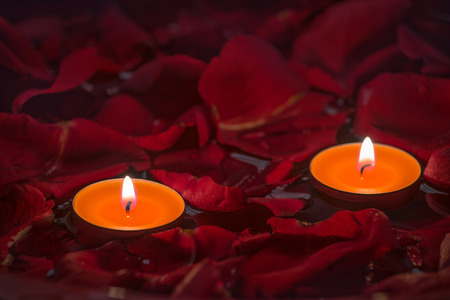 Two candles and red rose petals in waterの写真素材