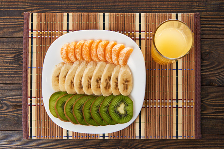 Slices of fresh fruit on a saucer and a glass of orange juiceの写真素材