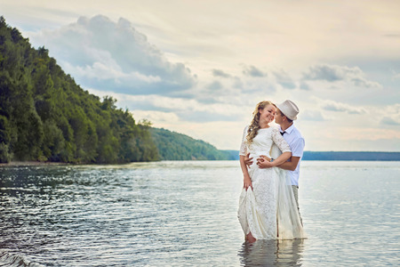 Bride and groom hugging standing in the waterの写真素材