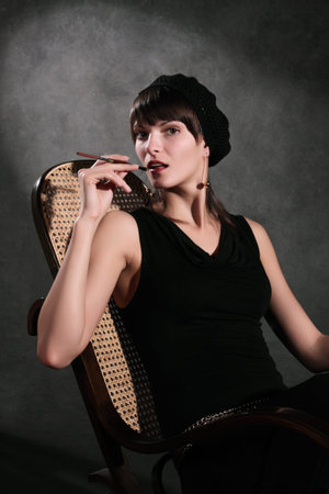 The girl sits in an armchair against a dark wall