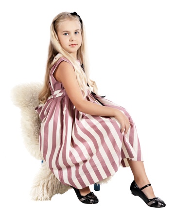 The girl in a striped dress sits on a chair, is isolated on a white backgroundの写真素材