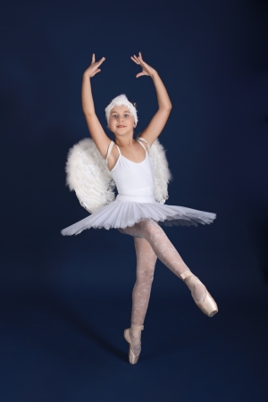 The ten years' girl dances in a ballet tutu on a dark blue backgroundの写真素材