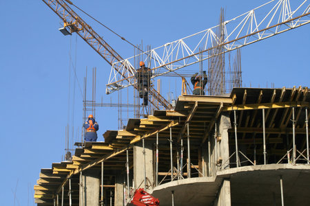 The workers connecting armature on a building site against the dark blue sky