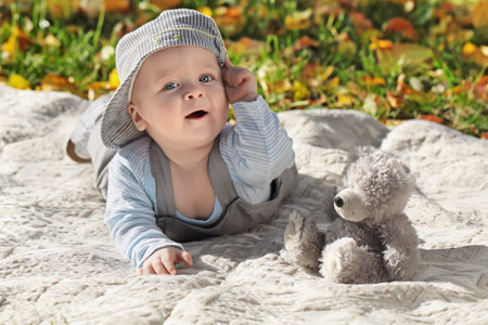 The child lies on a coverlet on the nature