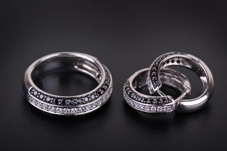 Ring from white gold and an earring with jewels on a black backgroundの写真素材