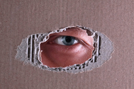 The man spies through a hole in a cardboard boxの写真素材