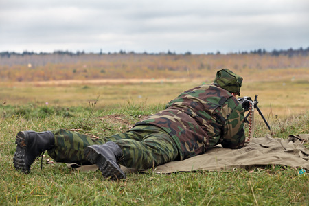 Soldier in camouflage uniforms with machine gun lying on the grass and fightsの写真素材