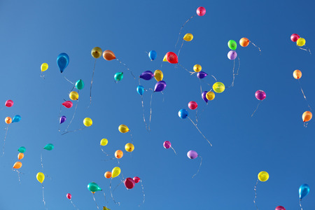 Balloons flying in the blue skyの写真素材