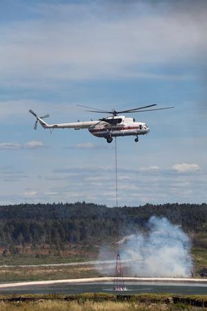 Fire helicopter draws up water from a fire reservoir for forest fire fightingのeditorial素材