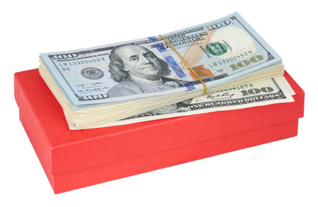 A stack of US dollars lies on a red box, isolated on a white backgroundの写真素材