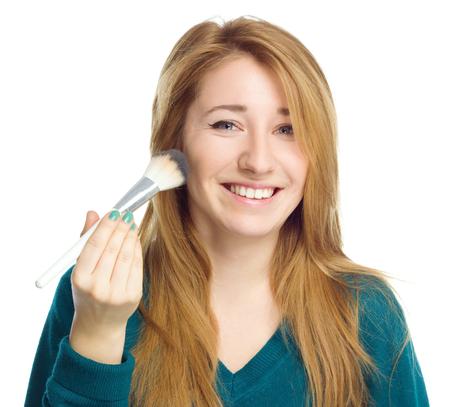 Girl is applying makeup using brush, isolated over whiteの写真素材