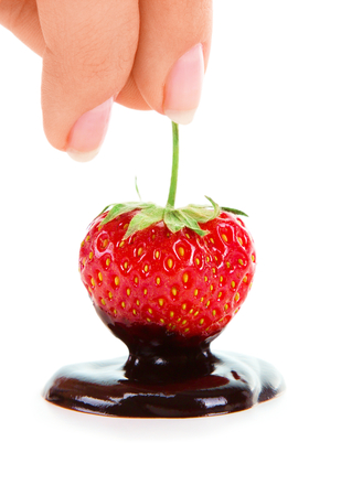Woman hand holding chocolate-dipped strawberry on the white backgroundの写真素材