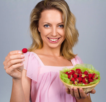 Close up of smiling woman holding raspberriesの写真素材