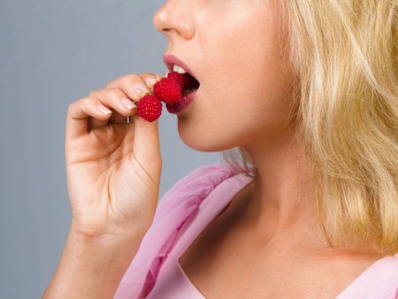 Beautiful woman eating sweet raspberriesの写真素材