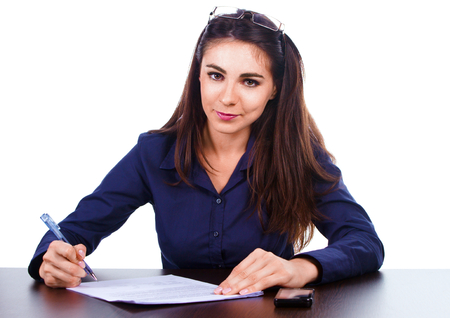 Portrait of a cheerful business woman sitting on her desk and sign up contract isolated over white backgroundの写真素材
