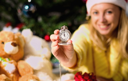 New Year clock in woman hands on christmas tree backgroundの写真素材