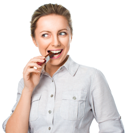 portrait of a young woman biting chocolate isolated on white backgroundの写真素材