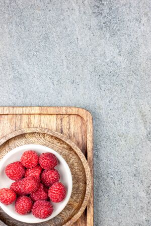 Rustic wooden plates on a concrete background, showing a mix of freshly picked berries. Raspberries, flat layの写真素材