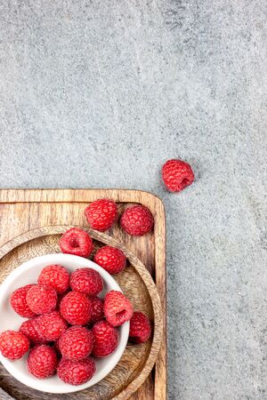 Rustic wooden plates on a concrete background, showing a mix of freshly picked berries. Raspberries, flat layの写真素材