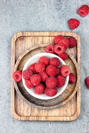 Rustic wooden plates on a concrete background, showing a mix of freshly picked berries. Raspberries, flat layの写真素材