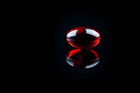 Close up of soft red gel medical capsule on black backgroundの写真素材