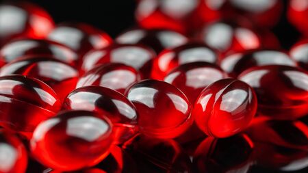 Close up of soft red gel medical capsule on black backgroundの写真素材