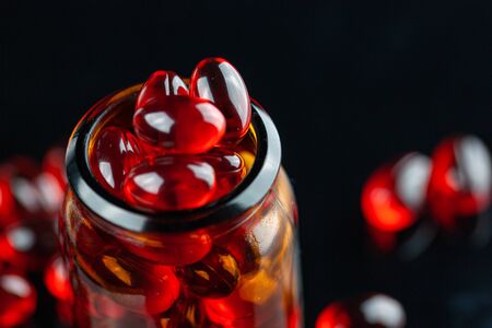Close up of soft red gel medical capsule on black backgroundの写真素材