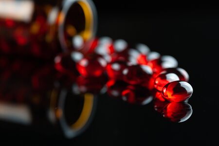 Close up of soft red gel medical capsule on black backgroundの写真素材