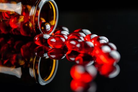 Close up of soft red gel medical capsule on black backgroundの写真素材