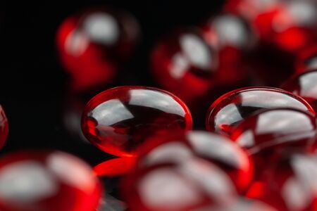 Close up of soft red gel medical capsule on black backgroundの写真素材