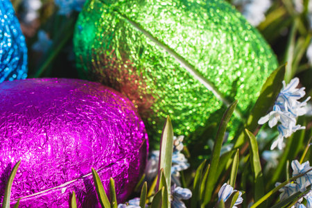 Colorful traditional swedish easter eggs, laying outside on field of white spring flowers. Egg...