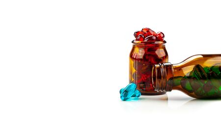 A mix of multicolored medical soft gel capsules on a white background - medical supplements , red, yellow, blueの写真素材