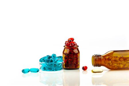 A mix of multicolored medical soft gel capsules on a white background - medical supplements , red, yellow, blueの写真素材
